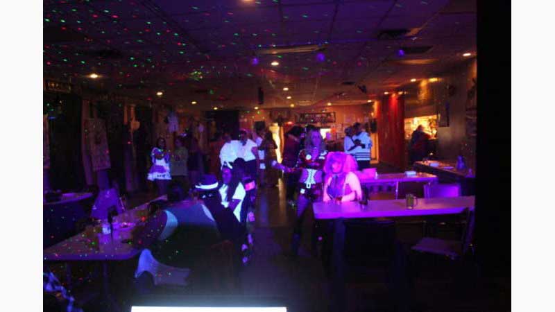 Light Show, DJ ST Catherines, Halloween party dark hall decorated for Halloween black light lighting the room with beautiful colors. A clown sit near the camera with her face lit up magically in UV makeup Taken in St Catherine's Ontario